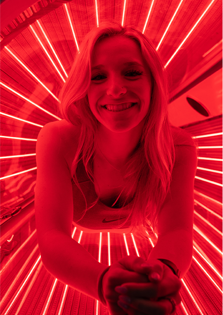 woman smiling in a 10X Health red light bed