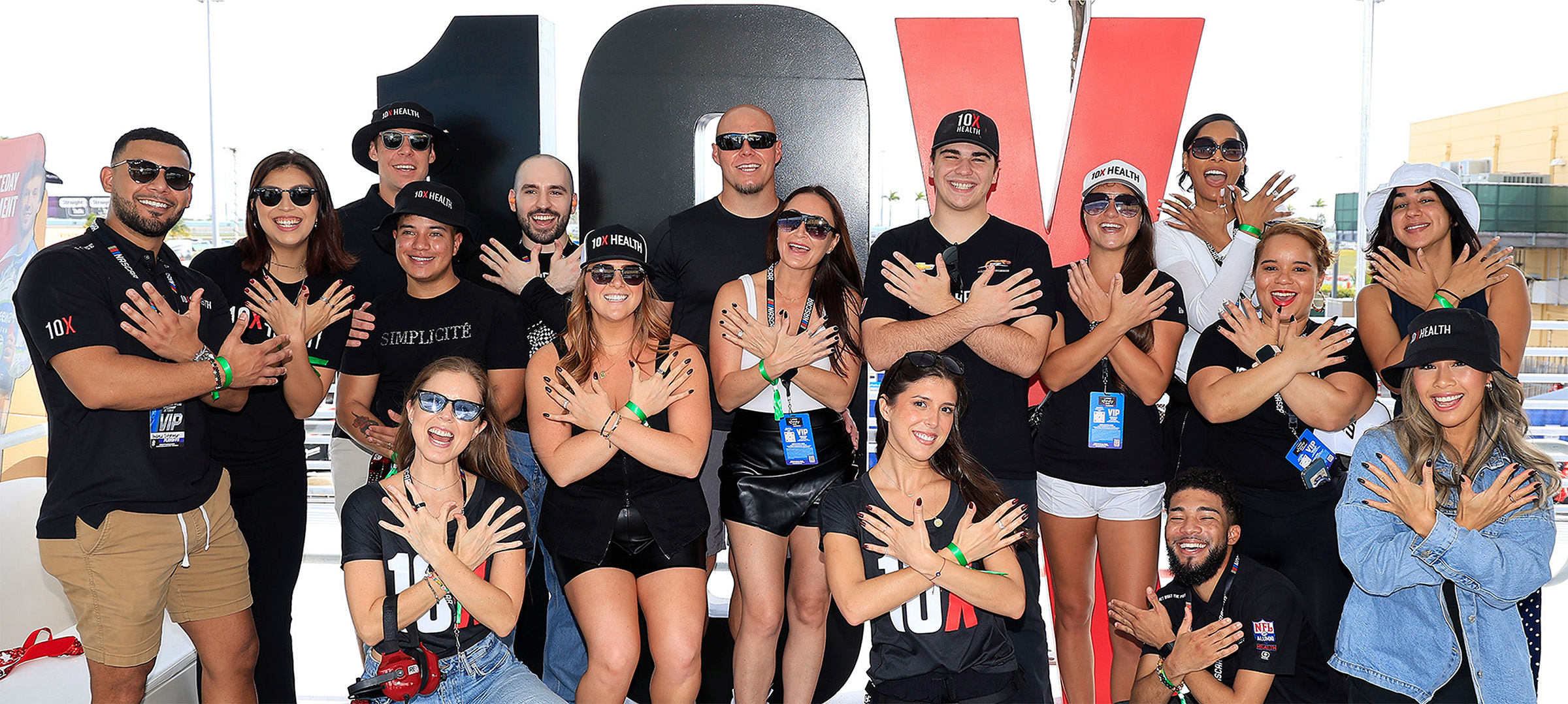 a group at a 10X Health event posing with their hands fanned out with ten fingers up a group at a 10X Health event posing with their hands fanned out with ten fingers up
