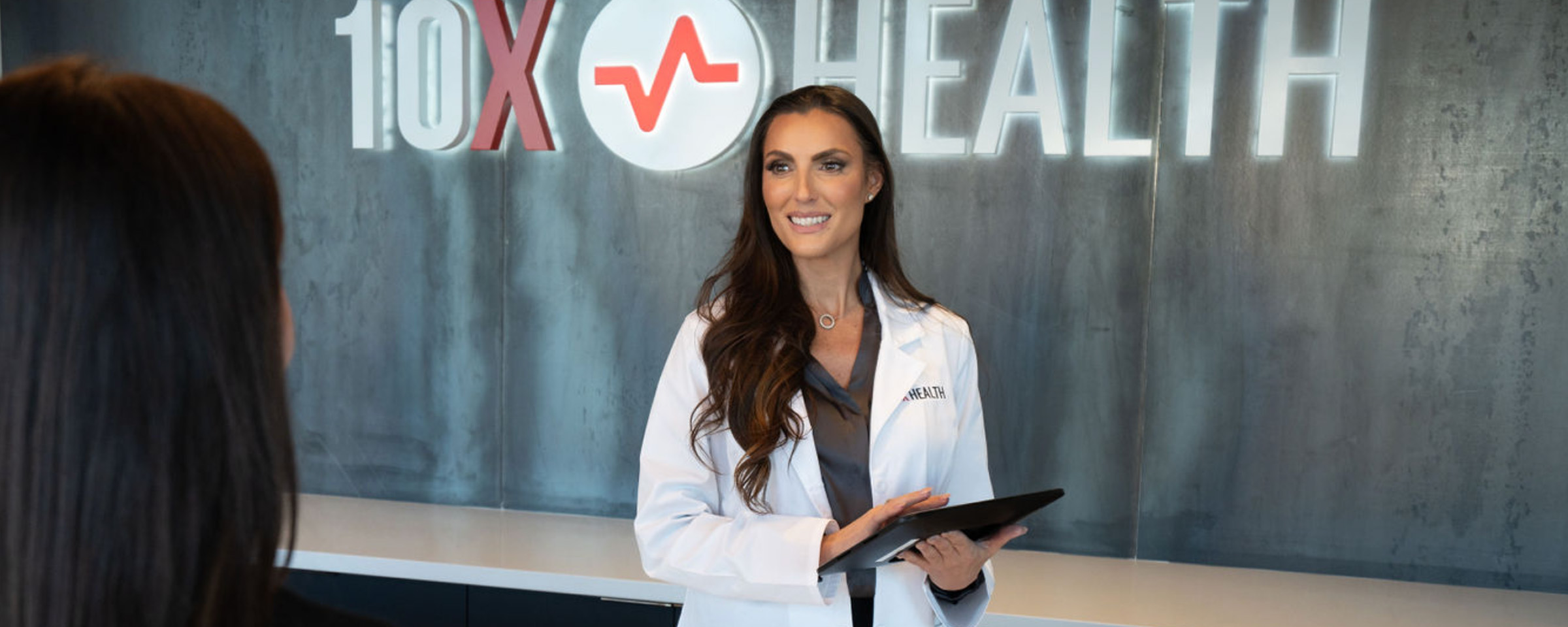 a 10X Health team member welcoming a visitor to a clinic a 10X Health team member welcoming a visitor to a clinic