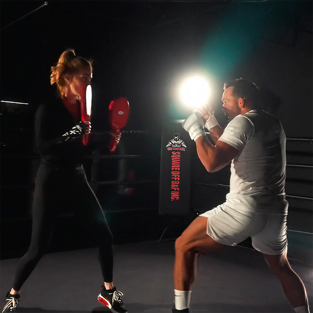 two people doing boxing exercises in a ring
