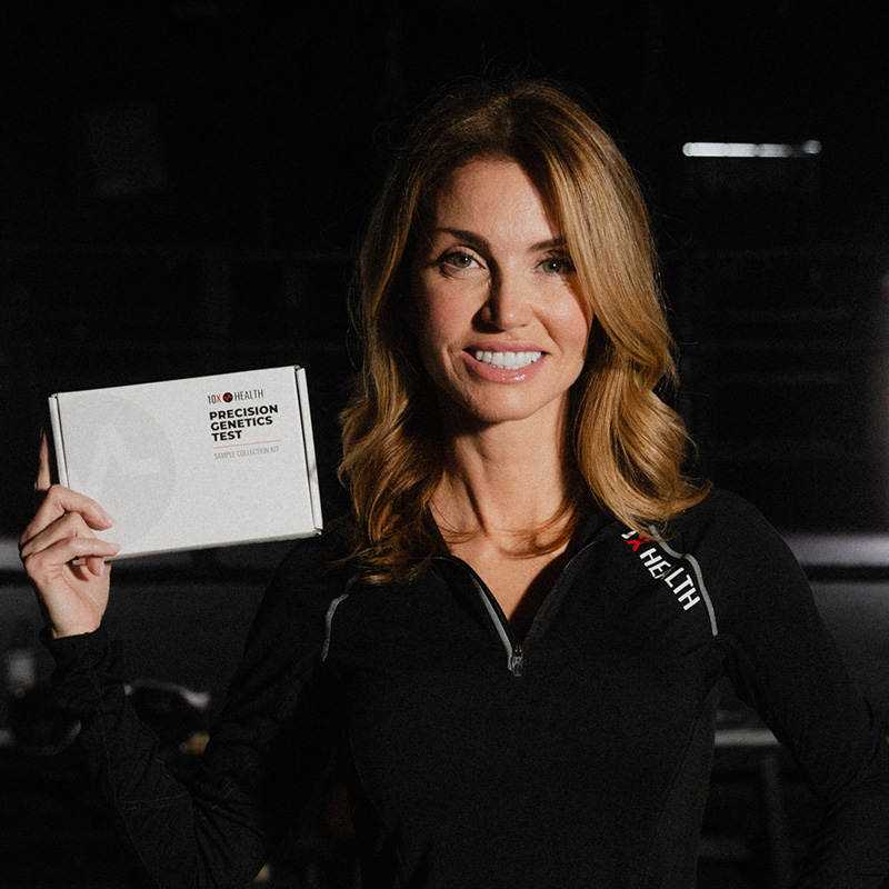 Elena Cardone stands in a dark training gym holding a 10X Health Precision Genetics Test