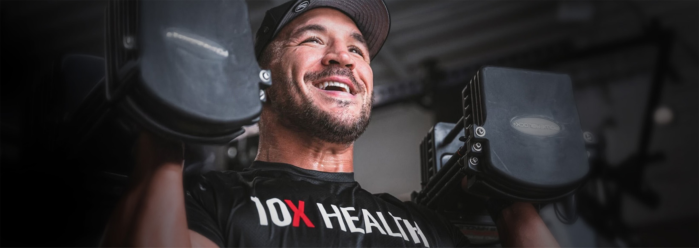 an athlete wearing a 10X Health System shirt smiles while lifting dumbbells