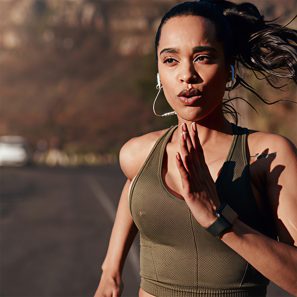 a woman running outdoors on a road while wearing headphones
